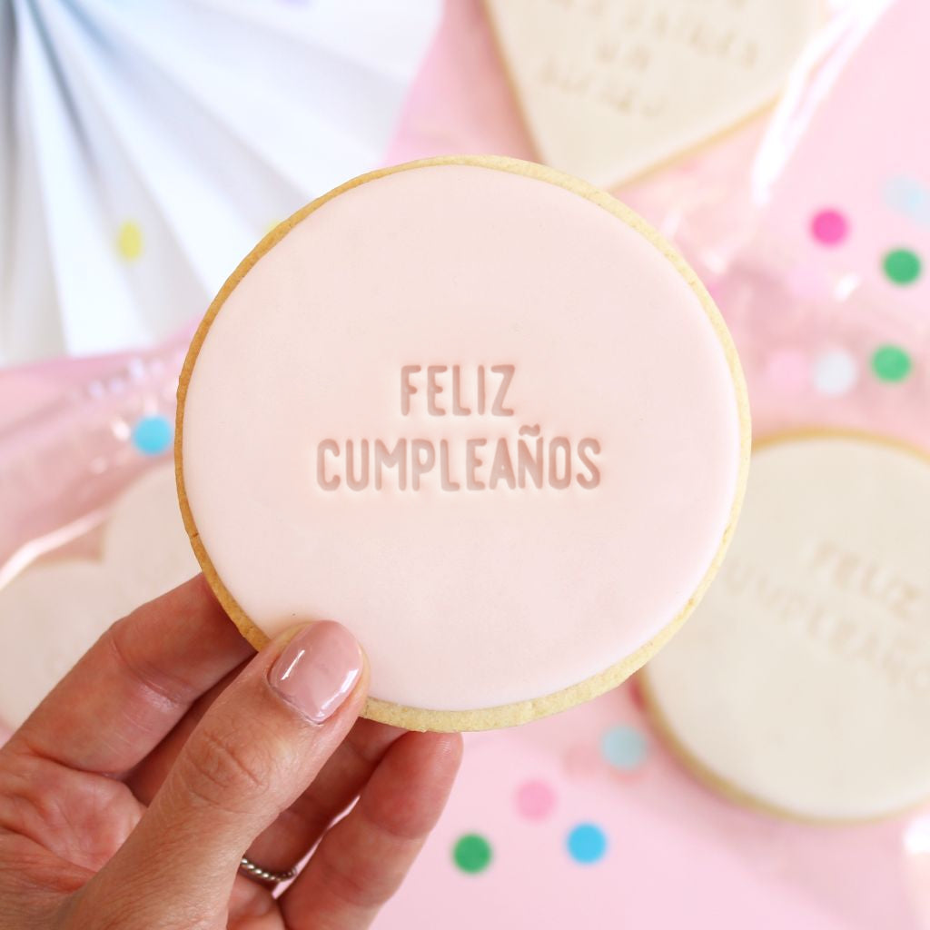 Galleta de mantequilla de color rosa pálido con forma redonda con la frase feliz cumpleaños impresa