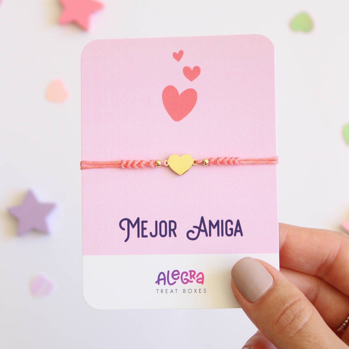 Pulsera de hilo color salmón con corazón de acero dorado en cartulina con la leyenda Mejor Amiga