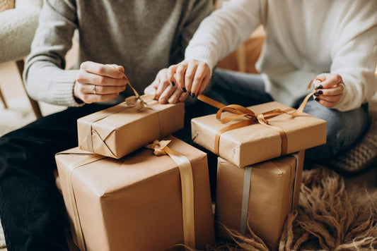 Una pareja abriendo varios regalos sentados en el sofá de casa 