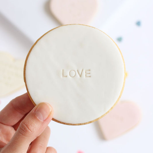 Galleta de mantequilla de forma redonda con la palabra love impresa